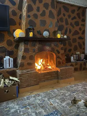 a brick fireplace with a fire in it at Chambre dans un magnifique petit riad avec piscine in Aghmat