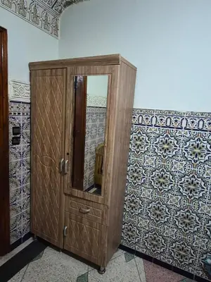 a wooden cabinet with a mirror on a wall at Appartement familial 110 m2 in Meknès