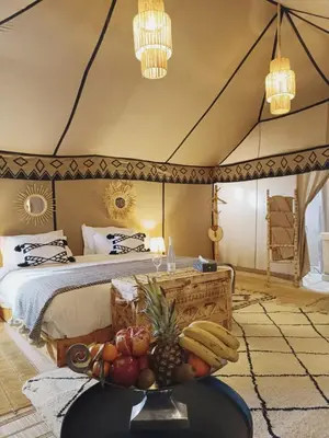 a bedroom with a bed with a bowl of fruit on a table at Sahara Spirit Luxury Camp in Merdani