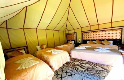 a room with three beds in a tent at Sahara Luxury Camp in Merzouga