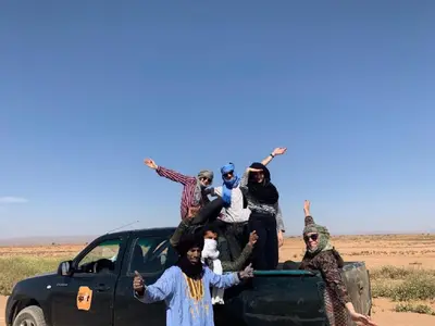 a group of people standing in the back of a truck at M'hamid Desert Camp Tours in Mhamid