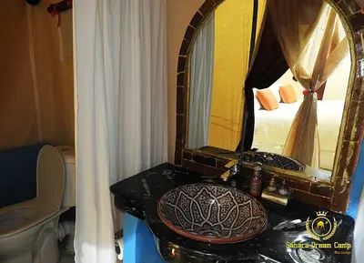 a bathroom with a sink and a mirror and a bed at Luxury Sahara Dream Camp in Merzouga