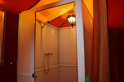 a shower with a glass door in a bathroom at Milky Way Desert Camp in Merzouga