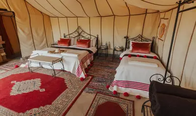 a bedroom with two beds in a tent at Tassili Luxury Desert Camp in Merzouga