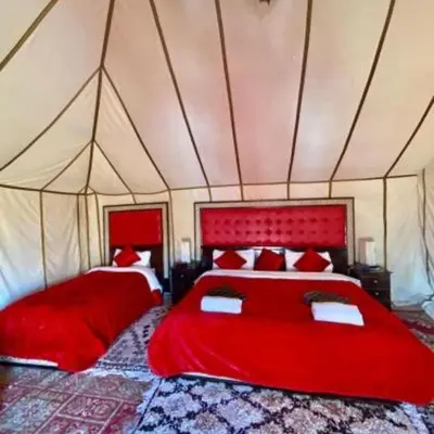 a bedroom with two red beds in a tent at Blue Sky Luxury Camp in Merzouga