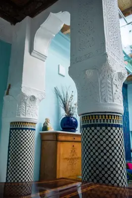 a white pillar with a blue vase on a table at Dar anne in Fès