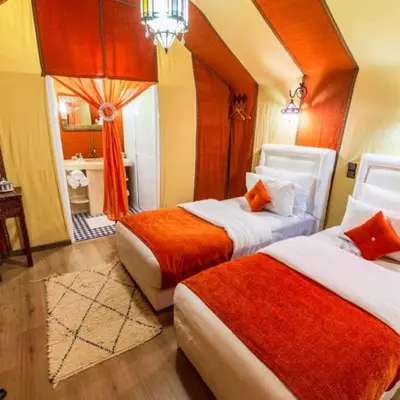 a hotel room with two beds and a bathroom at Deep Desert Camp in Merzouga