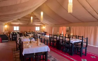 a dining room with tables and chairs in a tent at Bedouin Desert Camp in Merzouga