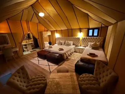 a room with a tent with two beds and a couch at Merzouga Desert Luxury Camp in Merzouga