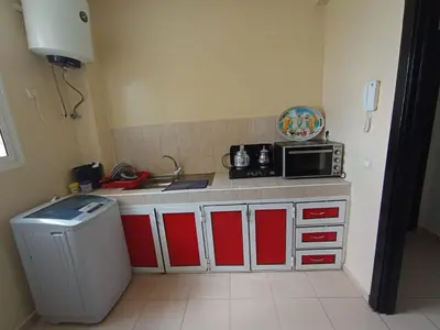 a kitchen with red and white cabinets and a microwave at Groupe appart-La casa de Wael in Ifrane