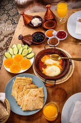 a wooden table topped with plates of food and fruit at Casa Mona in Merzouga
