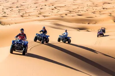 a group of people riding on quad bikes in the desert at Authentique merzouga camp in Merzouga