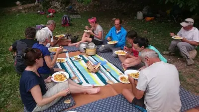 a group of people sitting around a picnic table eating food at Gte Tawada - Haut-atlas - Chambre pour 4 Personnes in Agouti