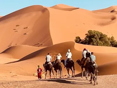 a group of people riding horses in the desert at Camel Luxury Camp in Merzouga