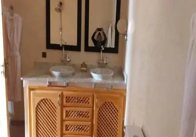a bathroom with two sinks and two mirrors at Riad Tin Hinane in Merzouga