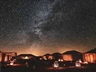 a starry night with a group of tents and the milky way at Sahara Events Camp in Merzouga