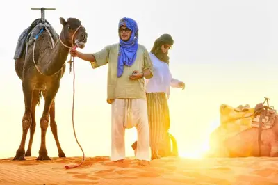 a man standing next to a horse in the desert at Erg Chebbi Desert Luxury Camp in Merzouga