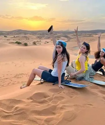 a group of women sitting in the desert at Apartement Rachid in Merzouga