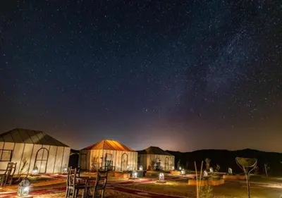 a cluster of buildings under a starry sky at night at Sahara Relax Camp in Merzouga