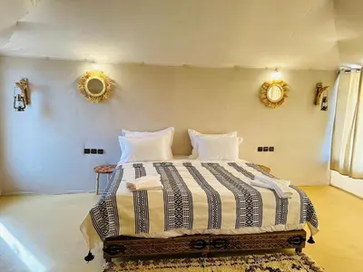 a bedroom with a large bed with two mirrors on the wall at Super Luxury camp in Merzouga