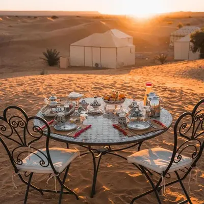 a table in the middle of the desert with a meal on it at Maktub Desert Luxury Camp in Merzouga